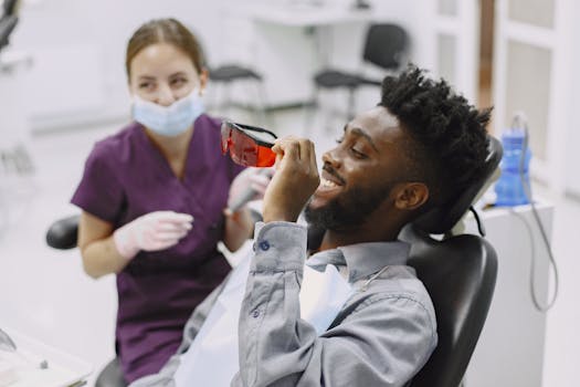 Man smiling and holding protective eyewear during a dental treatment in a clinic.